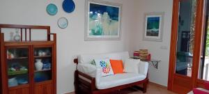 uma sala de estar com uma cadeira branca e uma almofada laranja em Lentisco terra e mare em Porto Azzurro