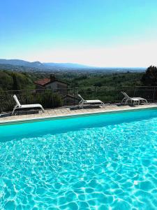 a swimming pool with chairs and a view of the mountains at B&B Hotel La Piana in Borgo a Buggiano