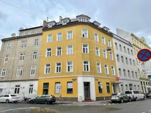 a yellow building with cars parked in front of it at Designer Apartments Asaria in Vienna