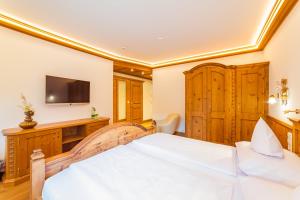 a bedroom with a large bed and a television at Via Salina - Hotel am See - Adults Only in Haldensee