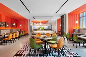 a restaurant with orange and green chairs and tables at Hampton by Hilton Foshan Beijiao in Foshan