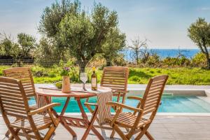 a wooden table with four chairs and wine glasses at Villa Vitalia in Lakithra