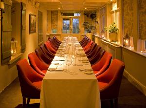 a long dining room with a long table and red chairs at Step House Hotel in Borris
