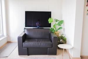 - un fauteuil en cuir noir dans le salon avec une télévision dans l'établissement holiday vibes! penthouse-studio near beach, à Ostende