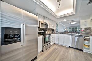 Una cocina con gabinetes blancos y electrodomésticos de acero inoxidable. en Loggerhead Cay #322, en Sanibel