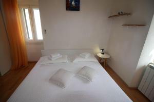 a white bed with two white pillows on it at Room Šolo in Sumartin