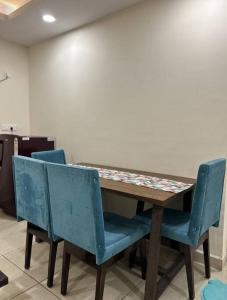 a wooden table with two blue chairs around it at Stylish Stay by Good Vibes Studio in Zirakpur