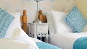 sypialnia z 2 łóżkami i białymi i niebieskimi poduszkami w obiekcie A Cosy Period Family Cottage in St Ives Town, sleeps 4, pet friendly w St Ives