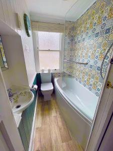 uma casa de banho com uma banheira, um WC e um lavatório. em A Cosy Period Family Cottage in St Ives Town, sleeps 4, pet friendly em St. Ives