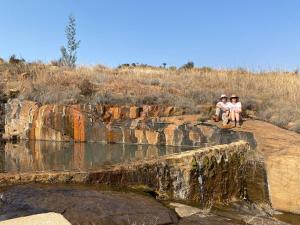 two people sitting on a rock near a body of water at Woolly Bugger Farm in Tonteldoos
