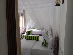 2 łóżka z białymi i zielonymi poduszkami w pokoju w obiekcie Forest Paddy Homestay w mieście Ella
