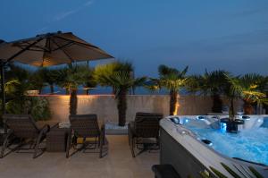 a hot tub on a patio with chairs and an umbrella at Jakuzzi Vila Suartini Orebić in Orebić