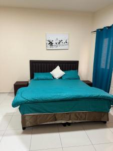 ein Schlafzimmer mit einem Bett mit blauen Kissen in der Unterkunft Fully Furnished Studio Appartment next to Sharaf DG metro Station in Dubai