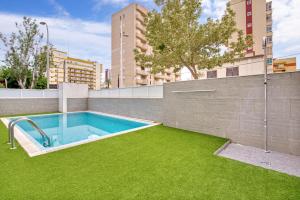 a swimming pool in a yard with green grass at Cala Blanca in Playa de Gandia