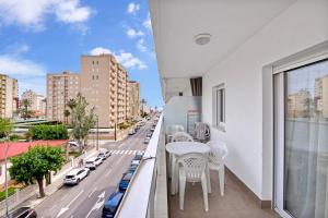 a balcony with white tables and chairs and a city street at Cala Blanca in Playa de Gandia