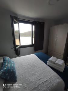 1 dormitorio con 1 cama y ventana con toallas en Casa Estife - Vivienda a pie de playa en Bares en Bares