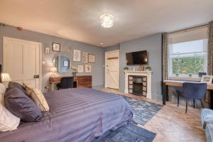 Un dormitorio con una cama, un escritorio y una chimenea. en The Darwin Malvern Suite, en Great Malvern
