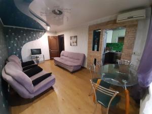 uma sala de estar com uma mesa de vidro e cadeiras roxas em Трёхкомнатные апартаменты em Krivoy Rog