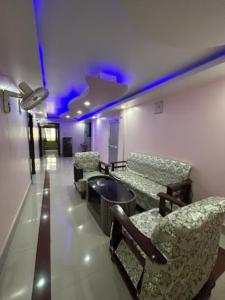um quarto com cadeiras, uma mesa e luzes roxas em Roop Amrit Guest House , Agartala em Agartala