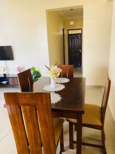 a dining room table with chairs and a vase of flowers at 2bedroom apartment in nyali in Mombasa