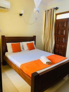 a bed with orange and white pillows in a room at 2bedroom apartment in nyali in Mombasa