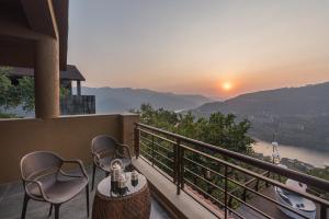 a balcony with two chairs and a table and a sunset at SaffronStays The Totem in Lavasa
