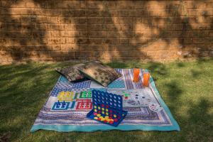 a blanket on the grass with balls and dominoes on it at SaffronStays The Totem in Lavasa
