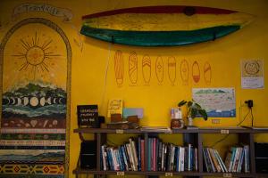 東河鄉的住宿－Dulan Tranquilo Hostel都蘭晃輕鬆青年旅舍咖啡館，墙上有书架和冲浪板的房间