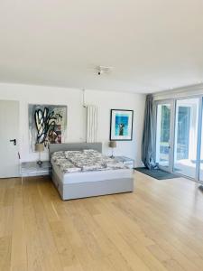 a white bedroom with a bed and a wooden floor at Mansion Lake Starnberg in Feldafing