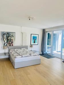 a white bedroom with a bed and a wooden floor at Mansion Lake Starnberg in Feldafing