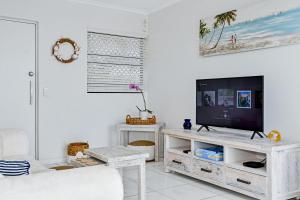 a living room with a television on a white cabinet at Coastal Chic Apartment - Mooloolaba and Alex in Alexandra Headland