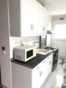 a white kitchen with a microwave and a sink at Amazing seaview apartment in Avliotes village Corfu in Avliótai