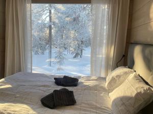 a bed with two pillows on it in front of a window at WALD Villas - Aavasaksa, Lapland in Aavasaksa
