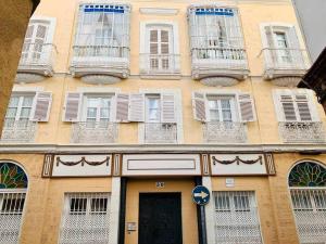 un edificio amarillo con ventanas blancas y una puerta en Las Gemelas de Benjumeda en la Caleta Grupo AC Gestion, en Cádiz