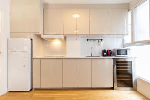a kitchen with white cabinets and a white refrigerator at Cosy flat close to Arc de triomphe in Paris