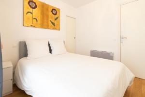 Un dormitorio con una cama blanca y una pintura en la pared en Cosy flat close to Arc de triomphe, en París
