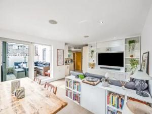 a living room with a large television and a table at Pass the Keys The Southside - Stylish Apartment with Private Terraces near Barnes & Putney in London