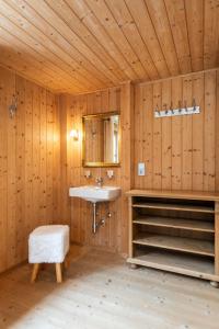 a bathroom with a sink in a wooden wall at Berghof Ferienhaus in Schröcken