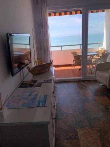 a living room with a television and a view of the ocean at El Mirador de la Playa Cortadura Grupo AC Gestion in Cádiz