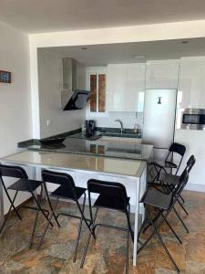 a kitchen with a white counter and black chairs at El Mirador de la Playa Cortadura Grupo AC Gestion in Cádiz