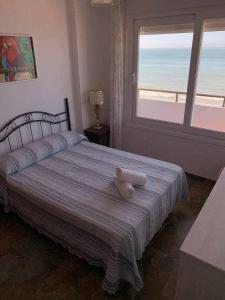 un osito de peluche sentado en una cama en un dormitorio en El Mirador de la Playa Cortadura Grupo AC Gestion, en Cádiz