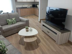 a living room with a couch and a tv and a table at Home Away in Vila Nova de Milfontes