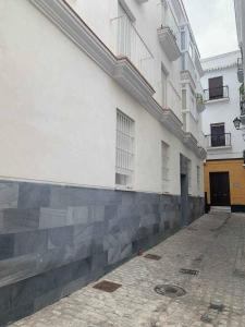 un grand bâtiment blanc avec un trottoir devant lui dans l'établissement Puerta de Santa Maria Grupo AC Gestion, à Cadix