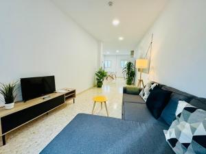 ein Wohnzimmer mit einem blauen Sofa und einem TV in der Unterkunft La Muralla Playa y Ascensor Grupo AC Gestion in Cádiz