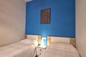 two beds in a room with a blue wall at Levante en el corazón de Cádiz WiFi Grupo AC Gestion in Cádiz