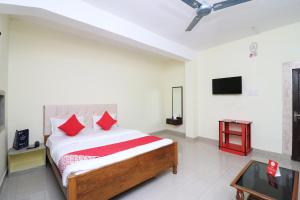 a bedroom with a bed with red pillows and a tv at OYO Flagship Hotel Shreya in Bhubaneshwar