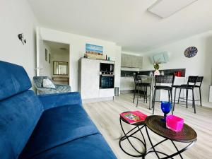 een woonkamer met een blauwe bank en een keuken bij Charmant appartement rénové 6 personnes les Sables in Les Sables-dʼOlonne