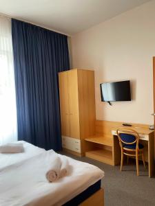 a hotel room with a bed and a desk and a television at Hotel Pod Zámkem in Boskovice