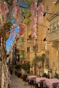 a street with pink flowers hanging from a building at City Penthouse with roof terrace and sea views in Valletta