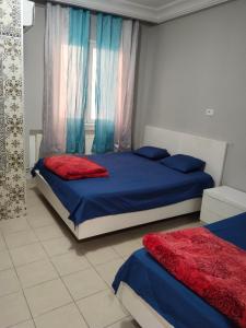 a bedroom with two beds with blue and red sheets at Hotel Marhaba - Beb Bhar Tunis in Tunis